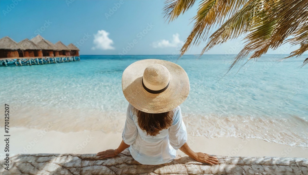 Woman in straw hat sitting on beach view from above. Summer vacation at Maldives Woman in straw hat sitting on beach view from above. Summer vacation at Maldives
