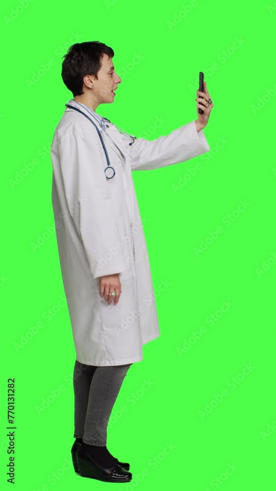 Profile Medic specialist having remote videocall conversation with patients on smartphone internet connection, greenscreen backdrop. Doctor discusses about disease with people on videoconference Profile Medic specialist having remote videocall conversation with patients on smartphone internet connection, greenscreen backdrop. Doctor discusses about disease with people on videoconference