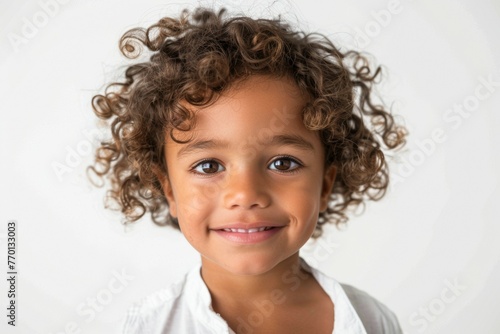 A young girl with curly hair is smiling at the camera