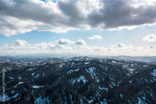 ドローン写真：雪が溶けつつある田舎の山と、広がる青空と雲