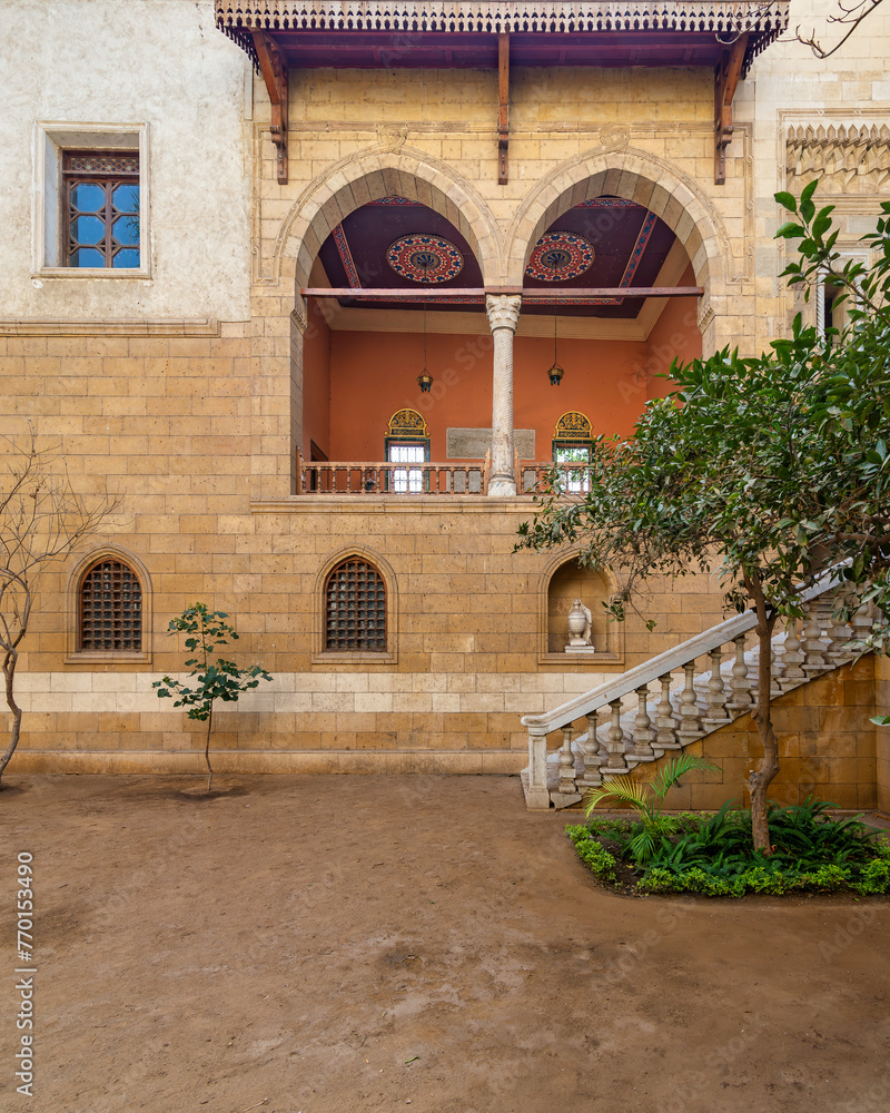 Serene courtyard showcases the timeless beauty of Mamluk architecture with high big arches and stonework with welcoming staircase leading to ornate balcony