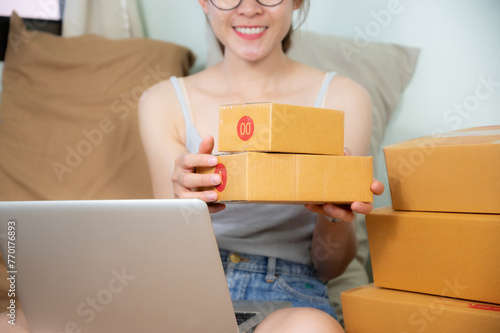 Asian woman packing her customer order in paper parcel box before sending it.