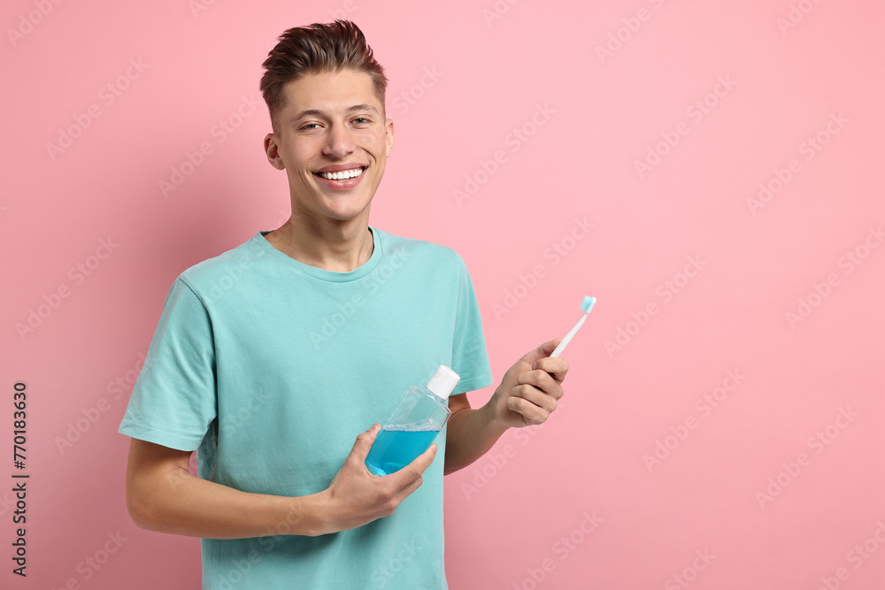 Young man with mouthwash and toothbrush on pink background, space for text Young man with mouthwash and toothbrush on pink background, space for text