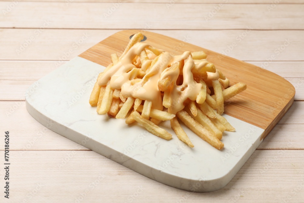 Delicious french fries with cheese sauce on wooden table