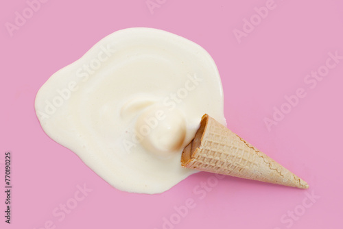 Melting ice cream ball with waffle cone on pink background. © Bowonpat