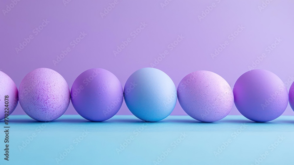A row of blue and purple Easter eggs are lined up against a purple background A row of blue and purple Easter eggs are lined up against a purple background