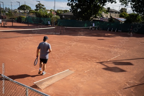 friends playing tennis on a clay court, watering and bagging a clay court. doing tennis court maintence