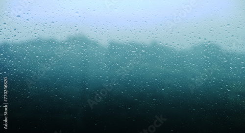梅雨 雨の滴のついた窓ガラスの奥の山の風景 6月・梅雨明け・水滴