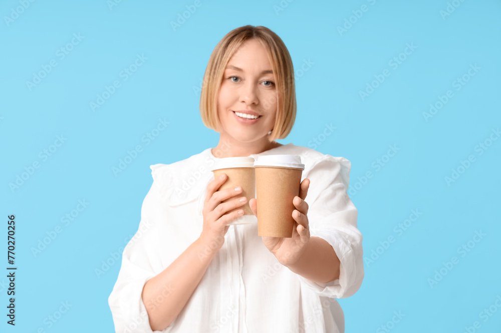 Happy adult woman with paper cups of coffee on blue background Happy adult woman with paper cups of coffee on blue background