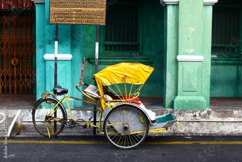 Horizontal shot of a yellow cycle rickshaw in Georgetown, Malaysia photo