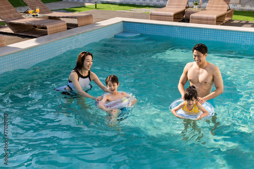 Happy young family having fun in swimming pool