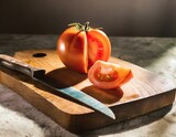 A vibrant, ripe tomato freshly sliced, its juicy interior glistening on a rustic wooden cutting board, with a gleaming knife beside it