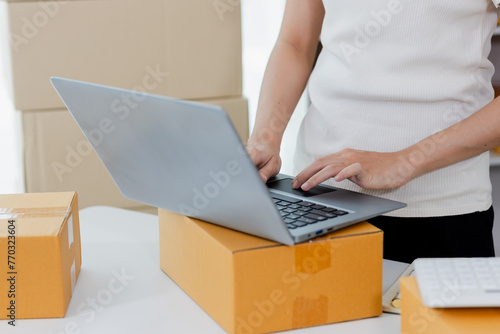 Startup small business entrepreneur or freelance Asian woman using a laptop with box, Young success Asian woman with her hand lift up, online marketing packaging box and delivery, SME concept. © Witoon