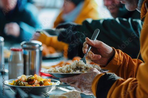 A person in a yellow jacket receives a hot meal in shelter, with steam rising from the plate. photo