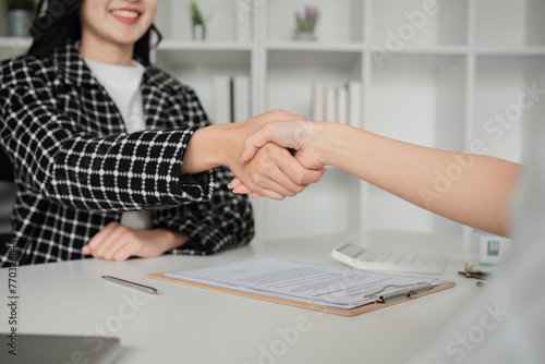 A real estate insurance agent joins hands to reach an agreement with a business customer for insurance for a home or real estate.