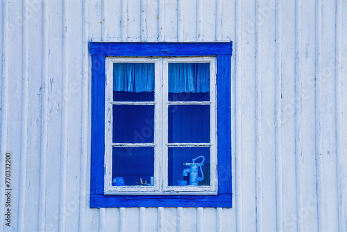 Blue window on white wooden cottage