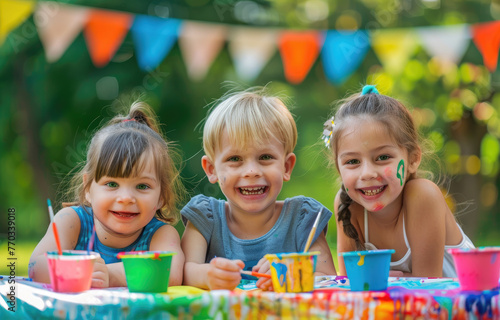 Fototapeta Naklejka Na Ścianę i Meble -  Three happy young kids having fun painting at an outdoor art class in the garden of their community, summer time