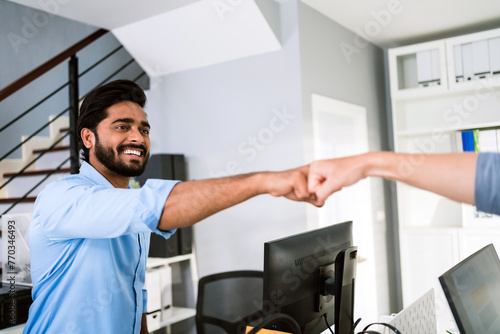 Cheerful Indian businessman partners making fist bump with a smile as a symbol of teamwork. Positive multi-ethnic business colleagues on diversity in the office. Collaboration concept