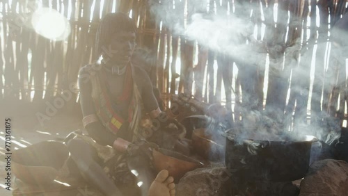 Hamer tribe Mother and daughter in a hut making food photo