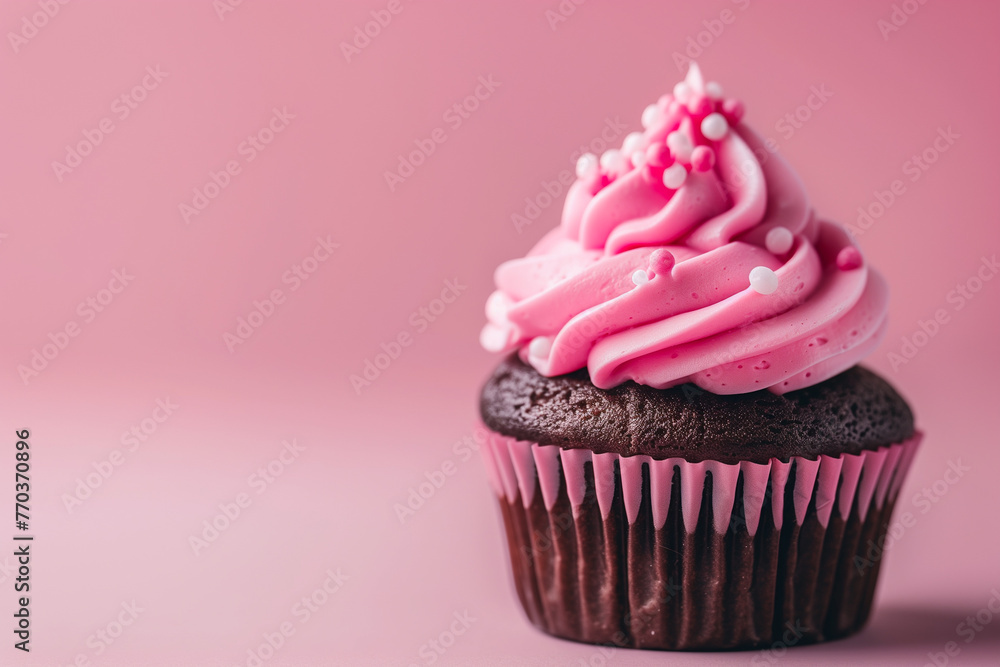 A delightful chocolate cupcake with pink frosting and sprinkles rests on a pink background A delightful chocolate cupcake with pink frosting and sprinkles rests on a pink background