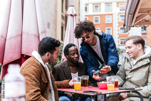 four multi ethnic friends drinking beers and talking photo