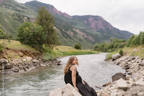woman sitting on a rock near Colorado river and mountains photo