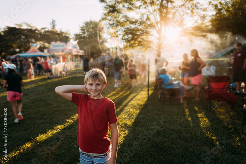 Child smiling at summer carnival during golden hour photo