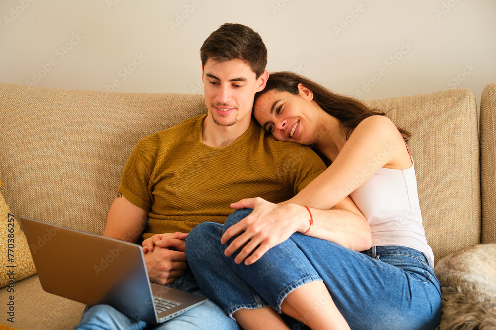 Spanish couple watching a movie on the laptop while hugging. Spanish couple watching a movie on the laptop while hugging.