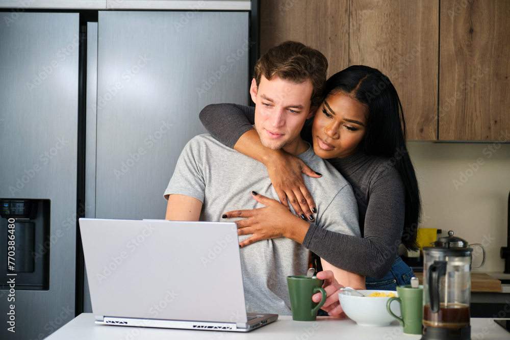 Multiethnic couple, man working while his wife hugging him. Multiethnic couple, man working while his wife hugging him.