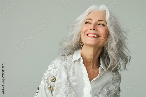 Portrait of a beautiful mature woman with white hair on gray background