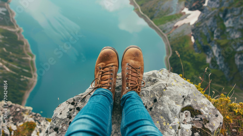 Perched atop a high mountain, a traveler's feet hang freely, embodying the concept of freedom.