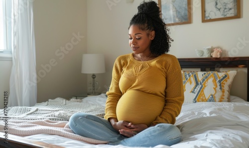 Pregnant woman with visible belly sitting on bed.