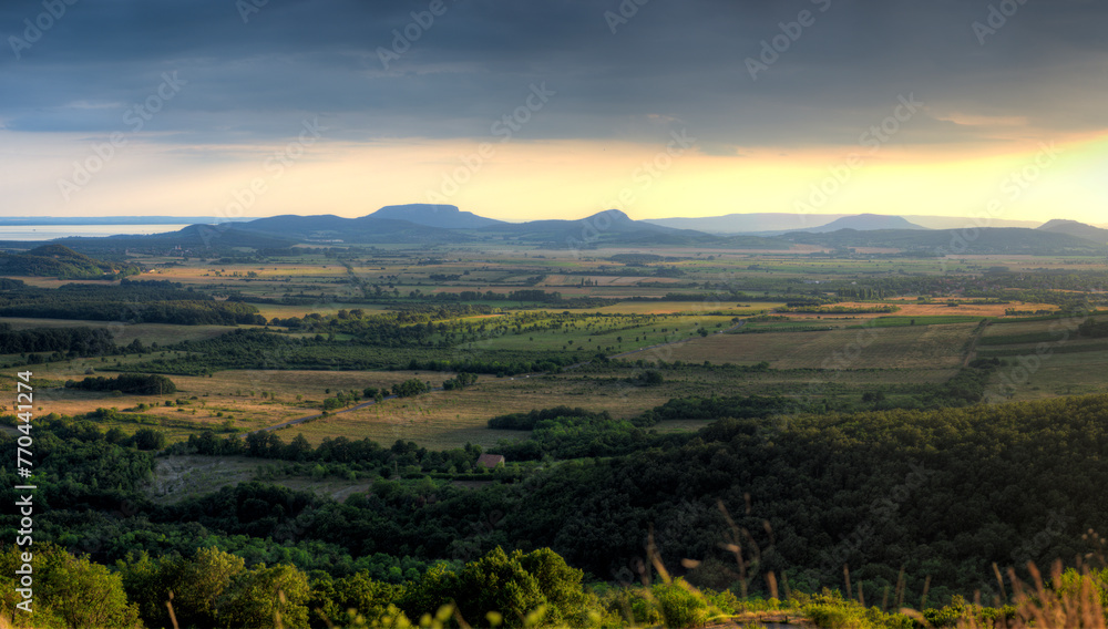 Ungarische Landschaft am Plattensee im schrägen Abend- oder Morgenlicht der Sonne mit ausgedehnten Feldern, Wäldern und Hügeln am leuchtenden Horizont