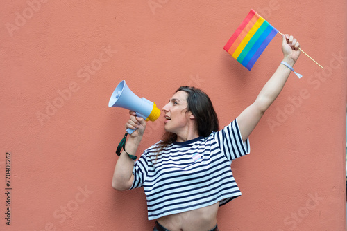 transgender LGBT hispanic celebrating rainbow flag and megaphone announcing equality isolated on nude colored background.