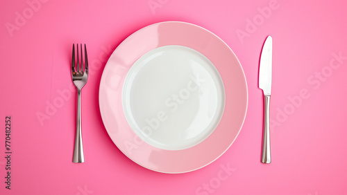 Empty pink plate with fork and knife on pink background, top view