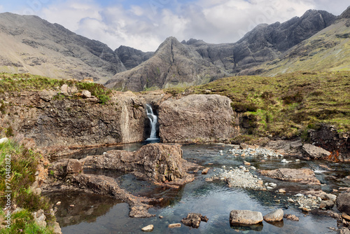 The crystal waters of the Fairy Pools flow through rugged rock formations, with Black Cuillin mountains providing a stunning backdrop on the Isle of Skye photo
