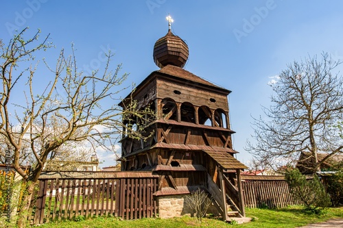 Wooden bell tower belonging to a wooden church in Hronsek, registered as a UNESCO World Heritage Site. Wooden historic bell tower, belfry. Spring atmosphere © Ivan