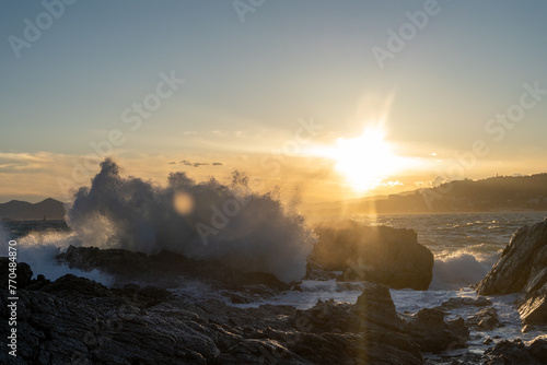 Waves crashing on cliffs at sunset. High quality photo