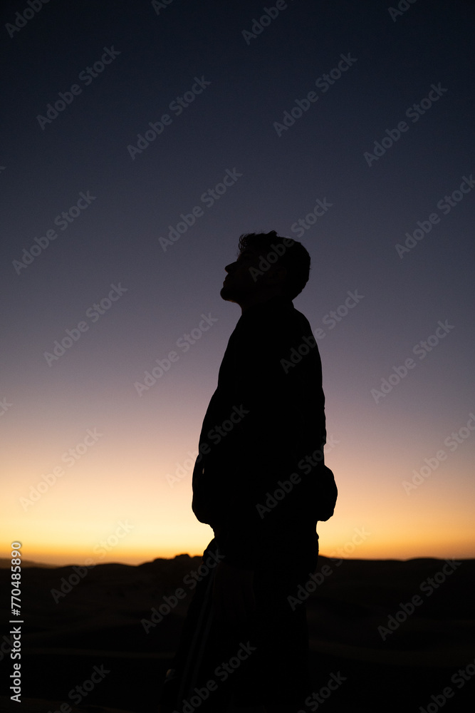 Vertical shot of a silhouetted man against a sunset background