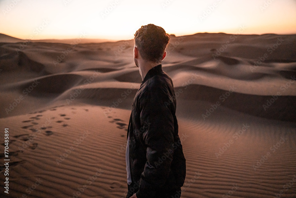 Young man gazing over the sandy desert at sunset Young man gazing over the sandy desert at sunset