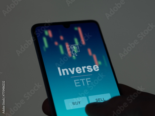 An investor analyzing the inverse etf fund on a screen. A phone shows the prices of Inverse