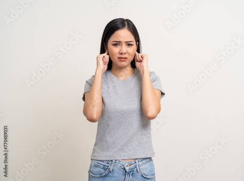 Young Woman stressed and frustrated covering her ears with her hands due to loud noise. Annoyed noise sound pollution. Asian Woman blocking ears