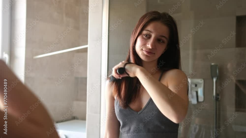 Teenage Girl Combing Her Hair In The Bathroom Mirror As Part Of Her Morning Routine After Waking Up Teenage Girl Combing Her Hair In The Bathroom Mirror As Part Of Her Morning Routine After Waking Up