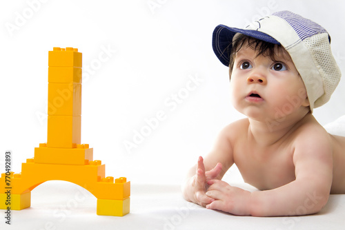 little boy on a white background lies with a toy Eiffel tower
