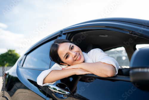 Young beautiful asian business women getting new car. Happy smiling female driving vehicle on the road Sticking her head outta the windshield with sun light. Business woman buying driving new car © Chanakon