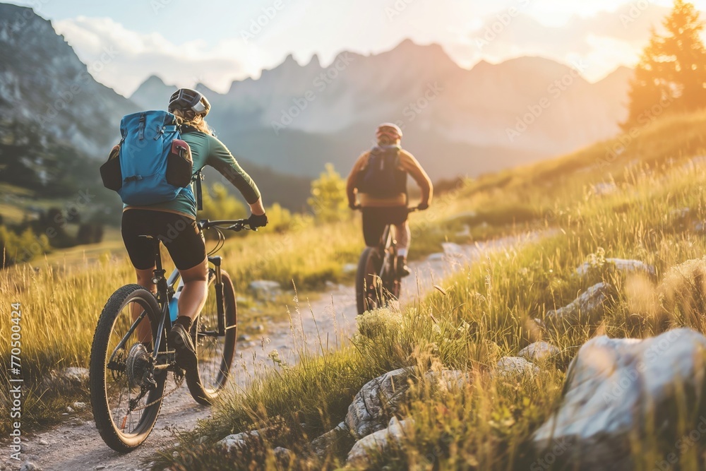 As the day wanes, cyclists are immersed in the warmth of the golden hour, pedaling through a meadow trail with the majestic mountains as their witness.