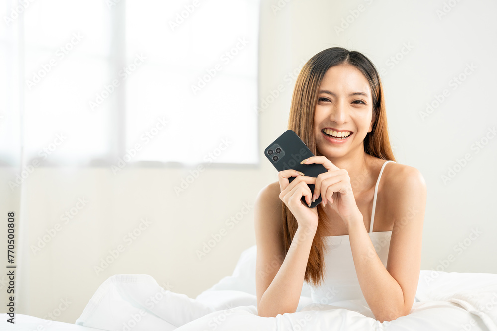 Pretty asian woman using smart phone on bed to social media at home in the morning. Lifestyle of young beautiful female using mobile phone to network internet online on the bed Pretty asian woman using smart phone on bed to social media at home in the morning. Lifestyle of young beautiful female using mobile phone to network internet online on the bed