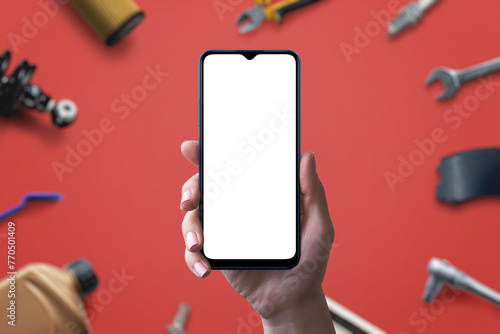 Phone mockup with isolated screen for app or web page promotion, backgrounded by car parts and tools. Concept of promoting a car parts sales page