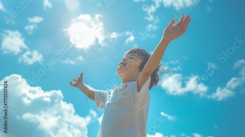 Happy boy with raising arms over blue sky at summer