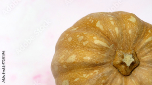 Small pumpkin with a pink marble background. With copy space on the left.